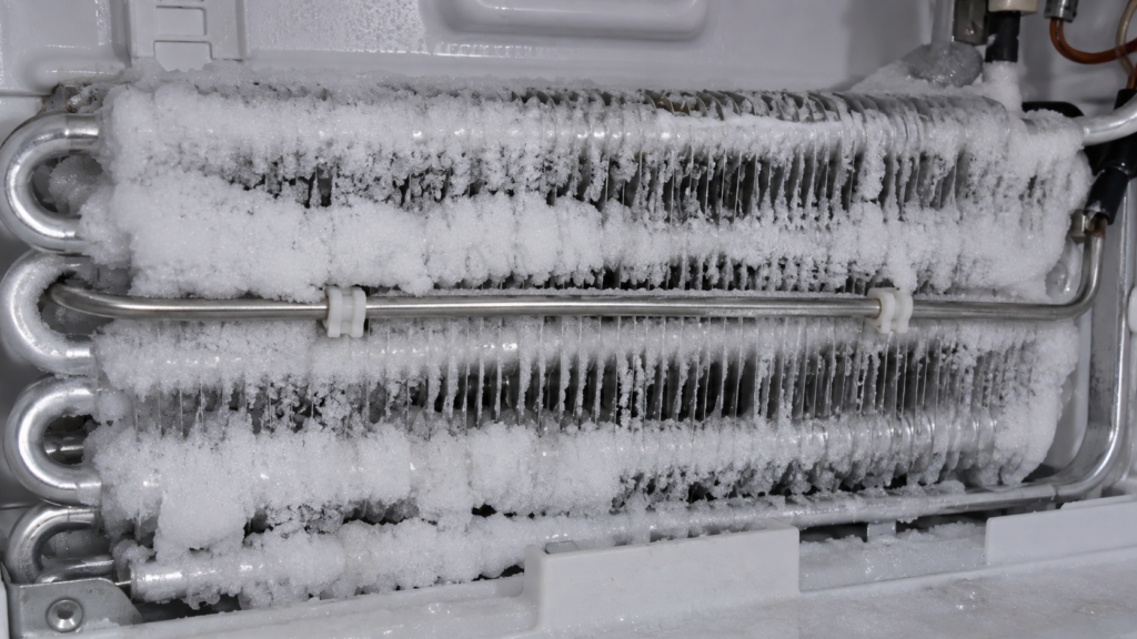 Close-up of the defrost heater rod running along a frosted evaporator coil inside a built-in freezer compartment.