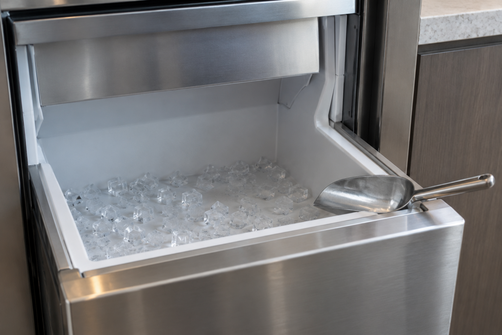 An open ice storage bin holding only a shallow scatter of clear cubes across its floor.